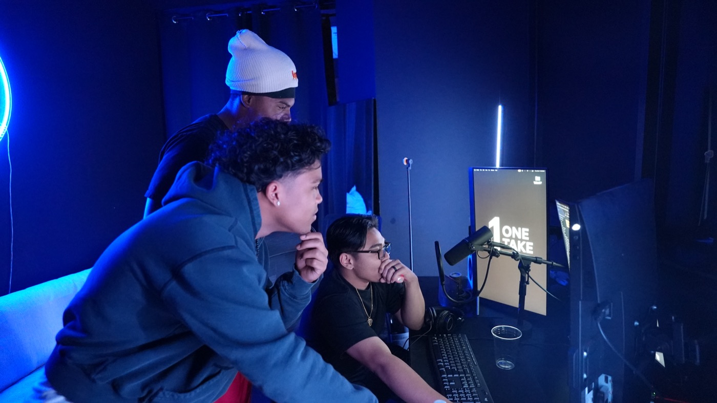 Three people gathered at the console reviewing a take