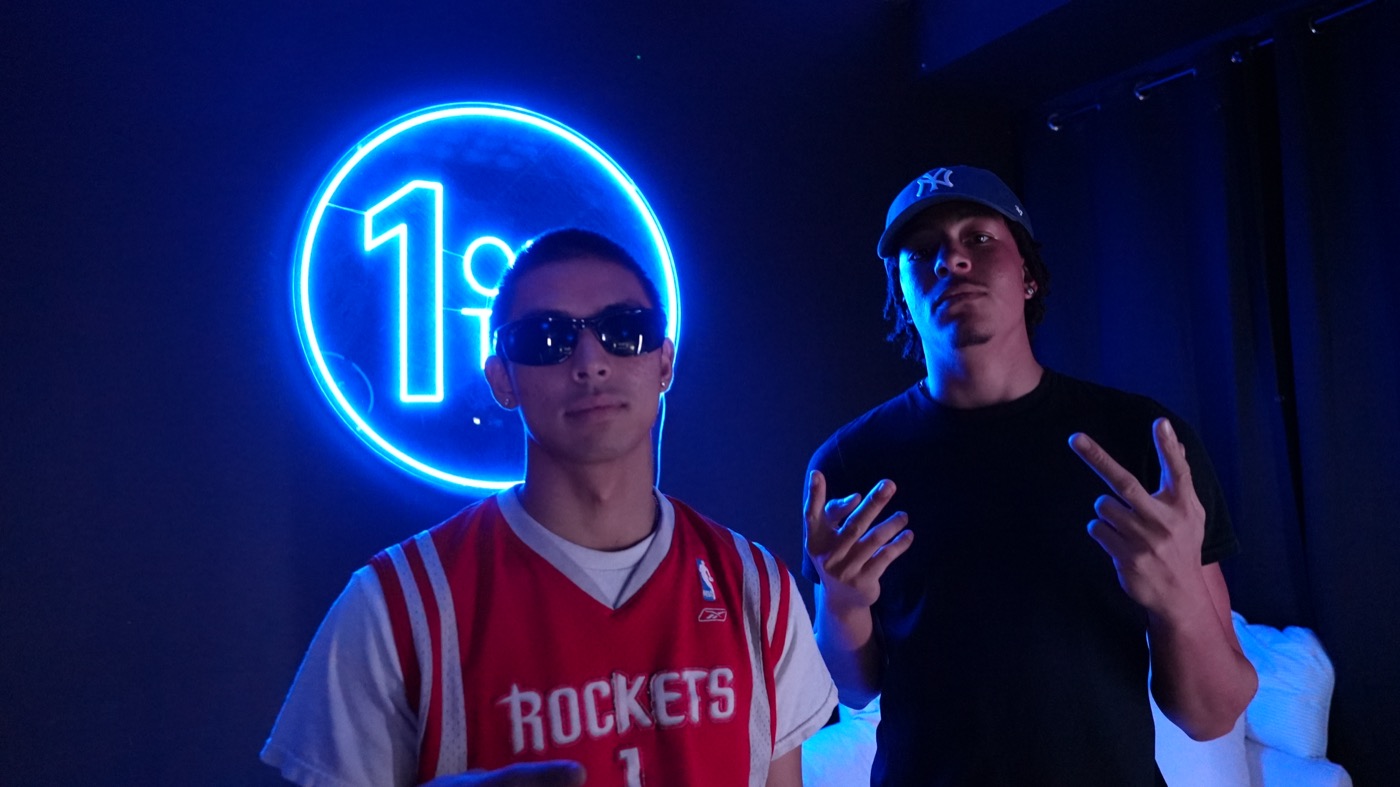 Two artists posing by the neon sign in the lounge