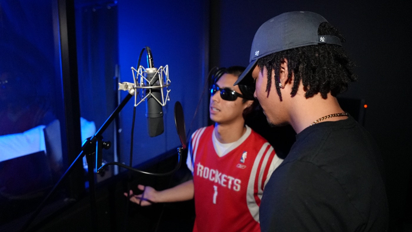 Two artists running a take together at the microphone